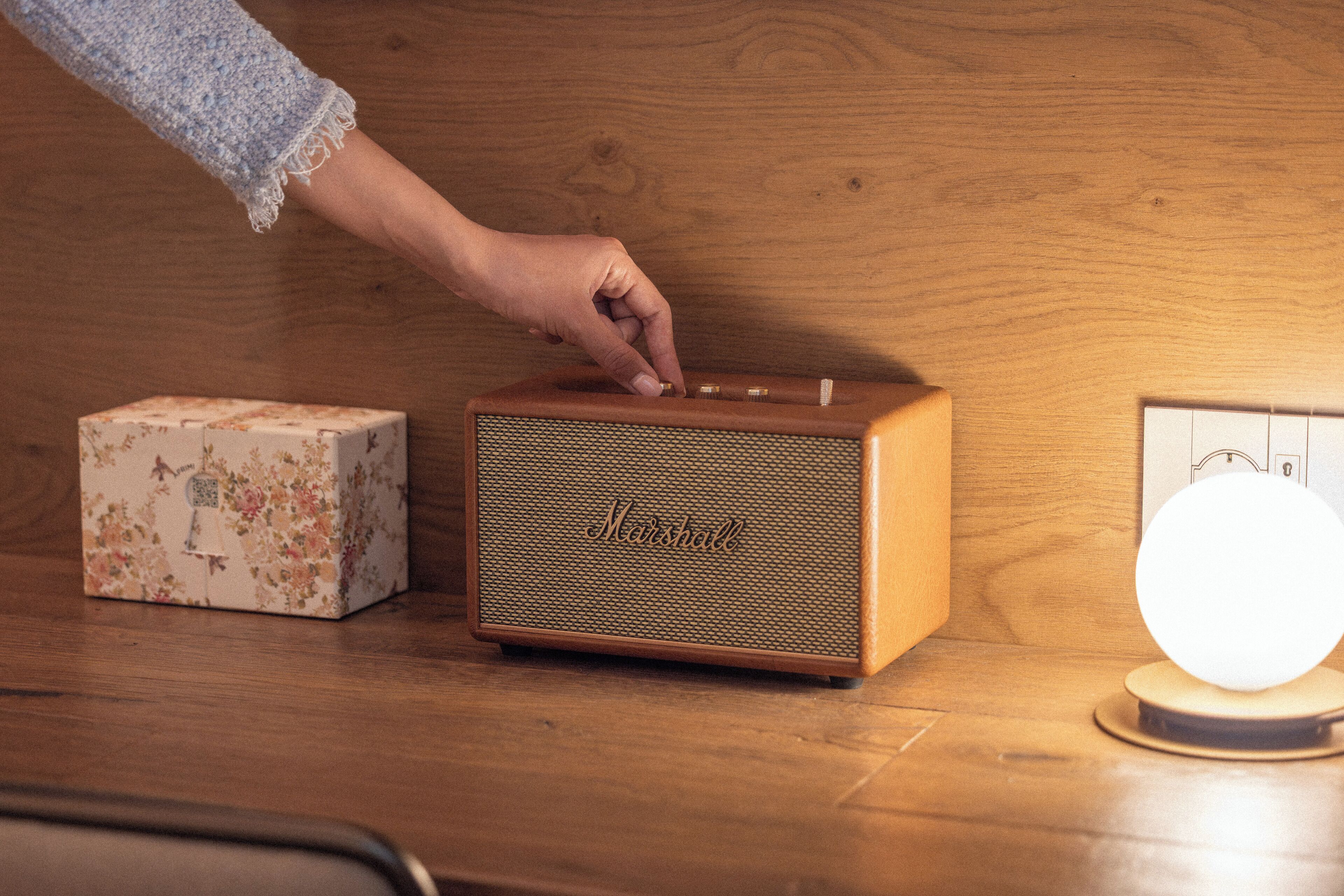A wooden table with a vintage Marshall speaker, a floral box, and a lit globe.