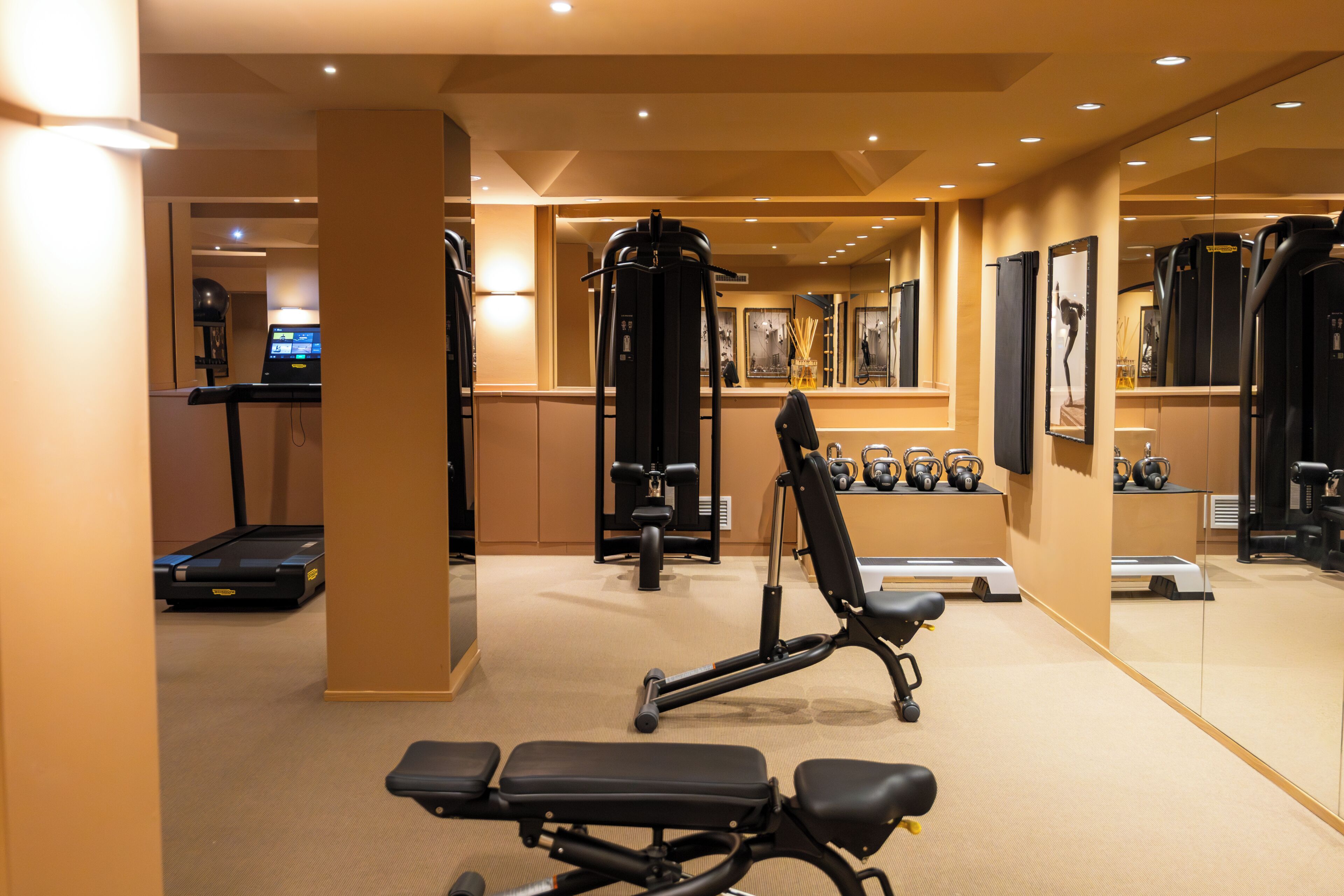 Un gimnasio con equipo de ejercicio, cinta de correr y pared espejada.