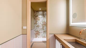 Un bagno con un mobile vanitario in legno, uno specchio e una doccia con carta da parati a motivi floreali.