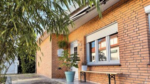 Une maison en briques avec une allée pavée, un banc et des plantes en pot.