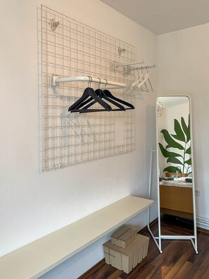 A room with a white wall, a grid-patterned hanging organizer, a mirror, a bed, and a wooden floor. - Cozy bungalow near the Teutoburg Forest (Augustdorf)