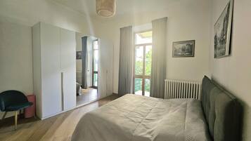 A bedroom with a bed, a chair, a wardrobe, and a radiator.