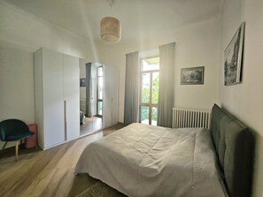 Un dormitorio con cama, una silla, un armario y un radiador.