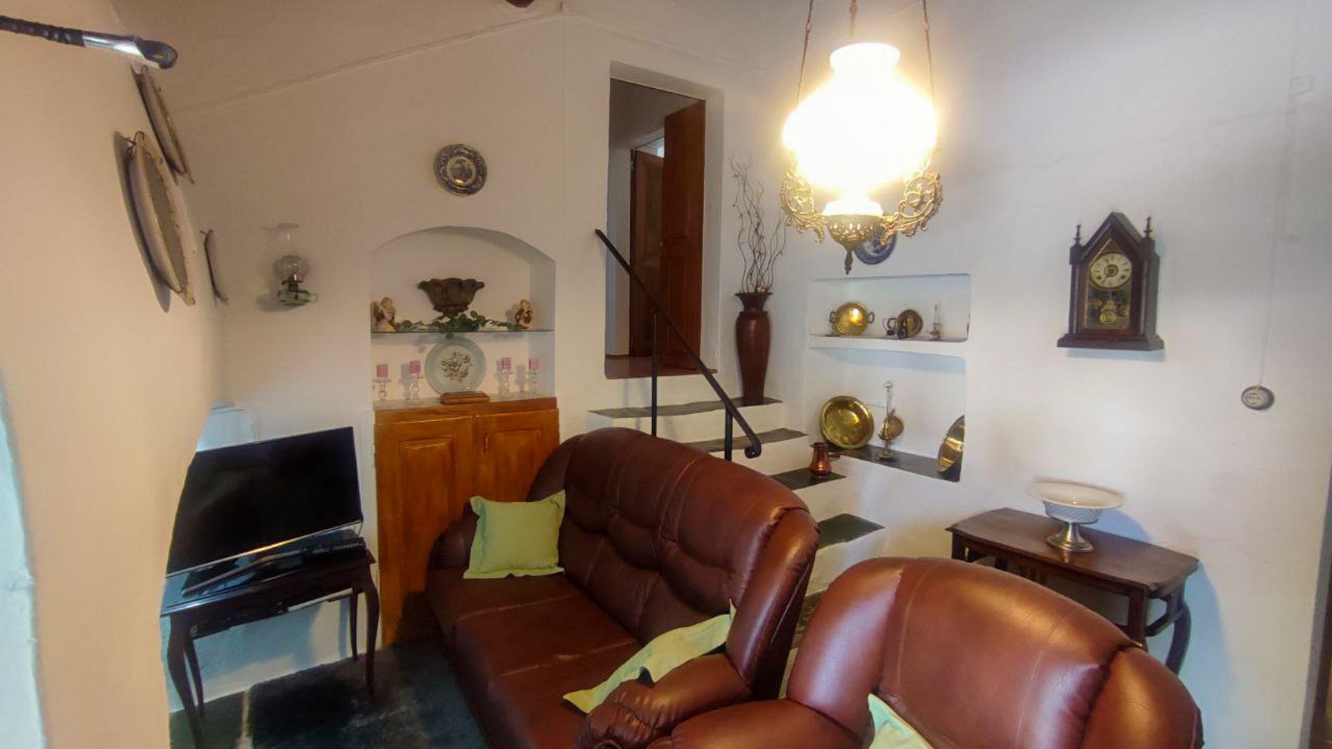 A living room with a brown leather sofa, a wooden cabinet, and a piano.