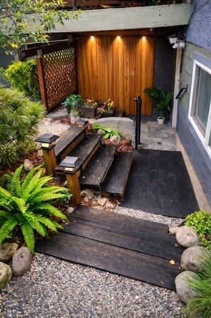 Una terraza de madera con bancos, una valla de madera y macetas con plantas.