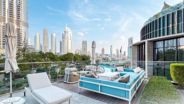 A rooftop terrace with a pool, seating area, and a city skyline view.