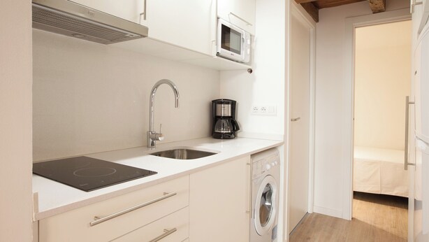 A compact kitchenette with a microwave, coffee maker, sink, and built-in oven. - Habitat Apartments Alissia (Barcelona)