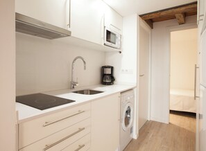 Una kitchenette compacta con microondas, cafetera, pileta y horno integrado.
