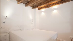 A bedroom with a bed, bedside table, and wall-mounted lights. - Habitat Apartments Alissia (Barcelona)