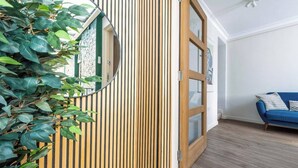 Una habitación con un muro de listones de madera, un sofá azul y un espejo que refleja parte del espacio.