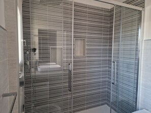 A modern bathroom with a glass shower enclosure, a built-in bench, and a large mirror. - Tiramisù included - By Flora (Treviso)