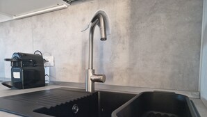 Ett modernt kök med en diskho i rostfritt stål, en inbyggd kaffebryggare och en stilren bänkskiva.