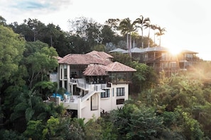 A multi-story house with a pool, surrounded by dense tropical vegetation.