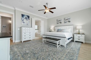A bedroom with a bed, bedside tables, a ceiling fan, and artwork on the walls.