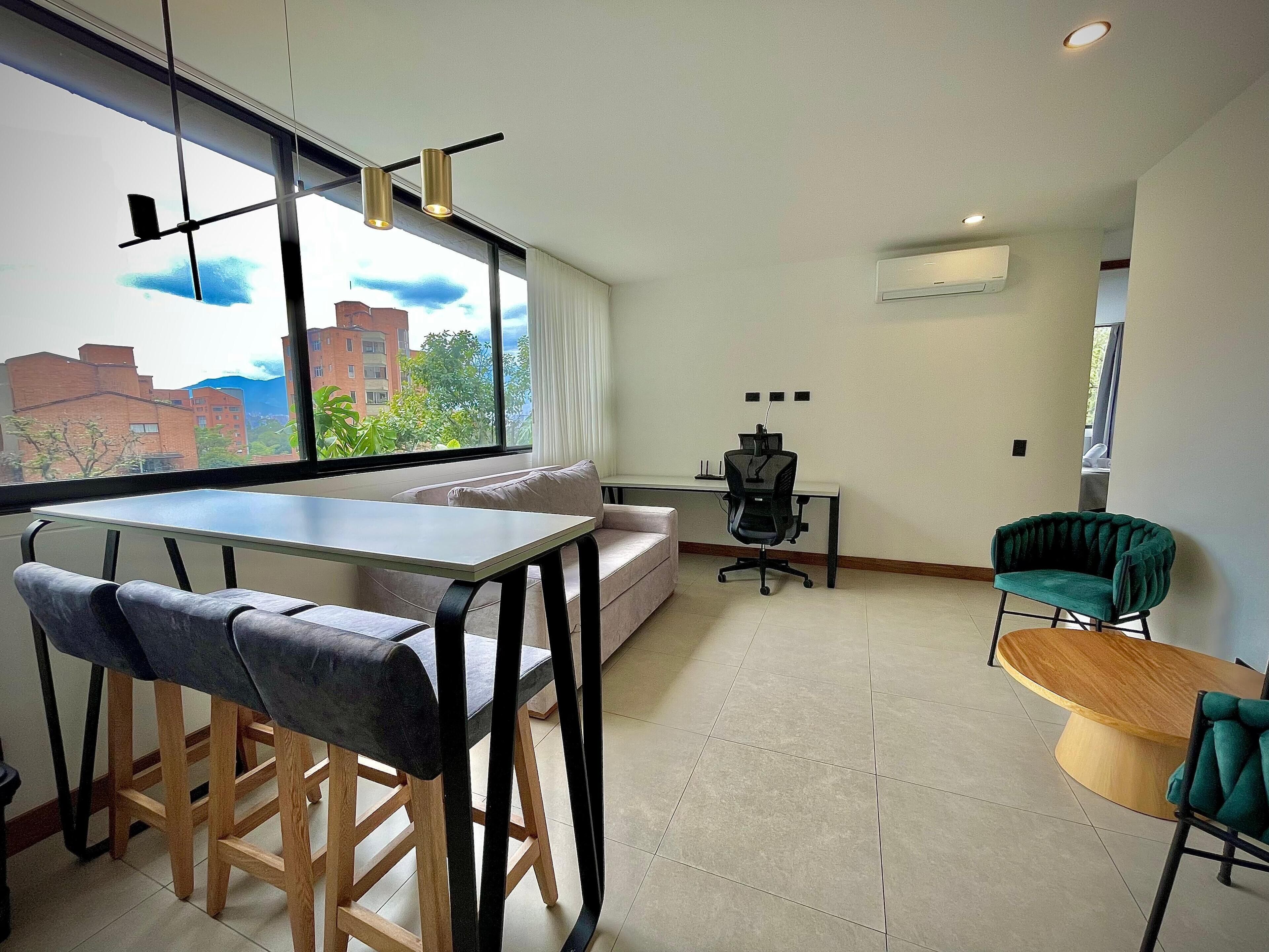 A modern living room with a sofa, a dining table, and a workspace with a chair.