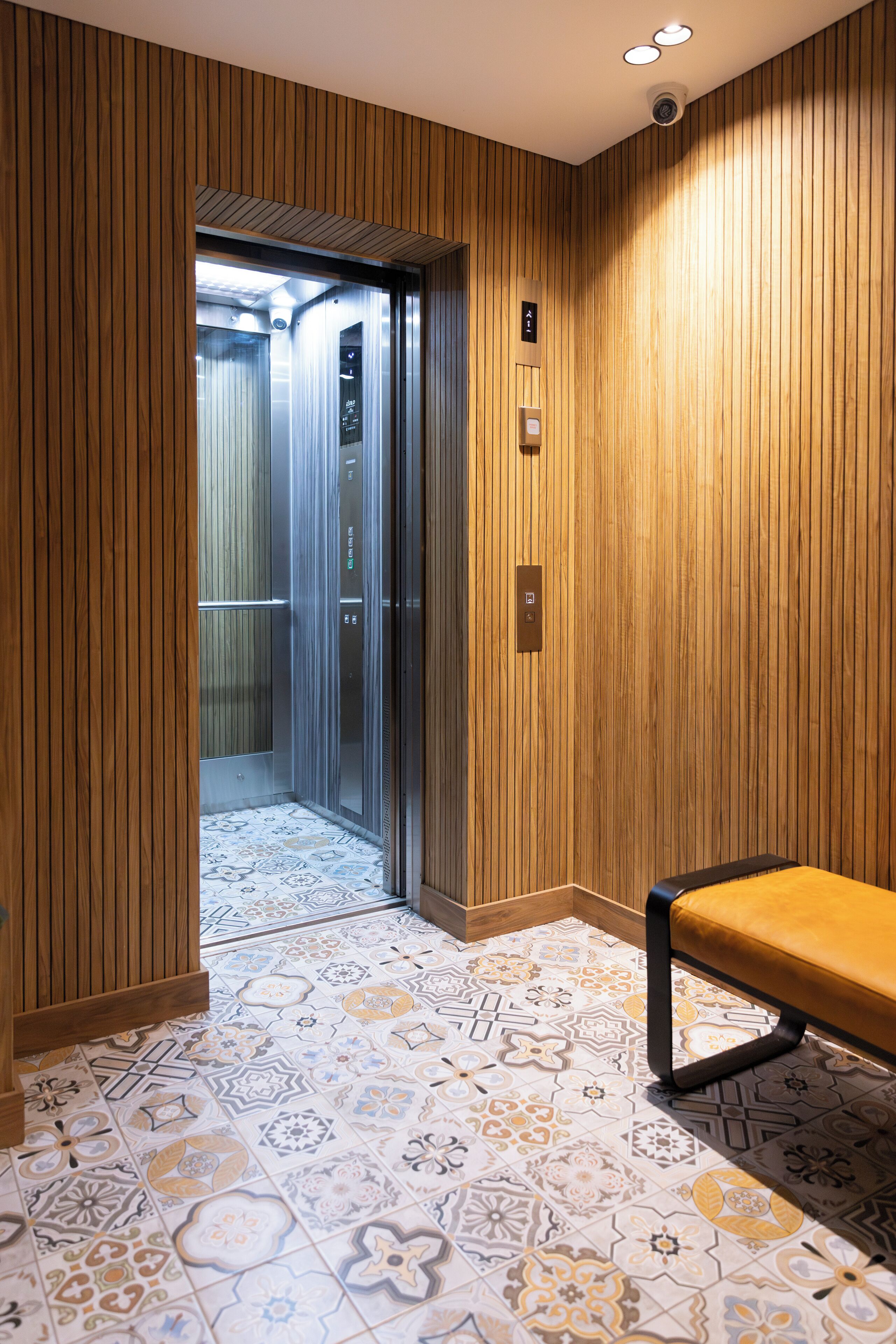 An elevator with a wooden panel wall and a patterned tile floor.