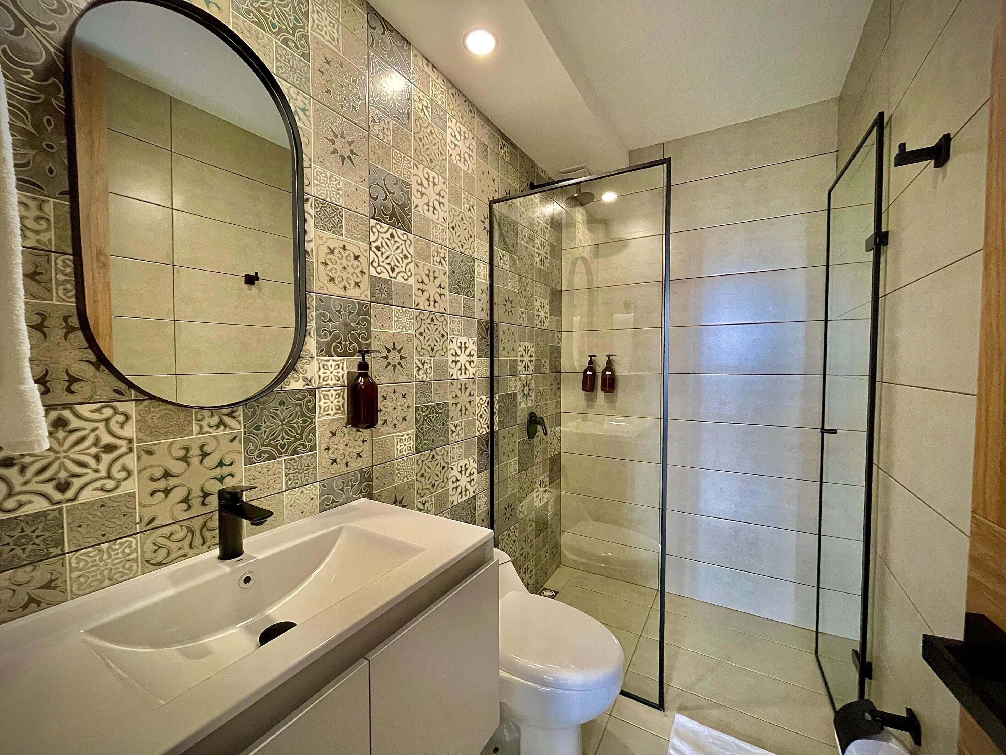 A bathroom with a sink, toilet, and glass shower enclosure.