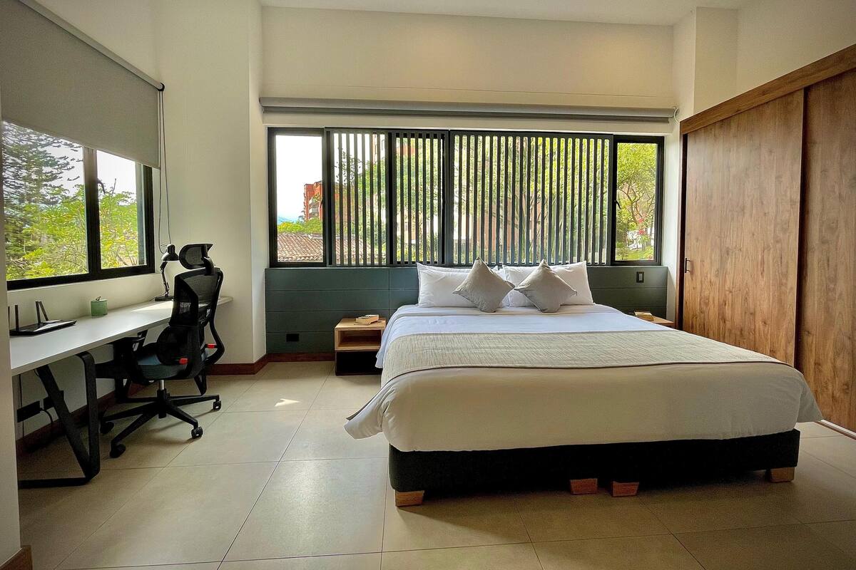 A modern bedroom with a large bed, a desk, and a chair.
