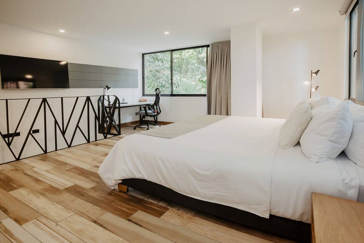 A modern bedroom with a large bed, a desk, and a chair.