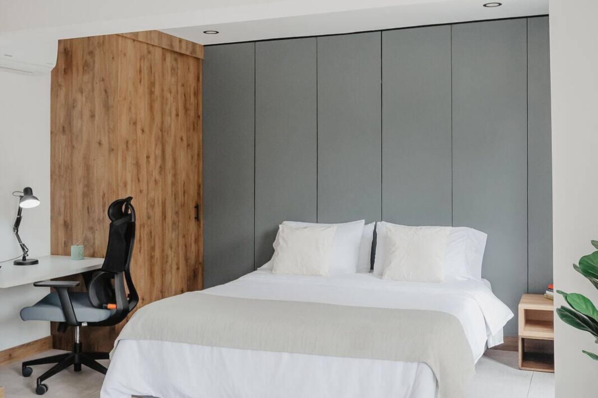 A modern hotel room with a large bed, a desk with a chair, and a wooden accent wall.