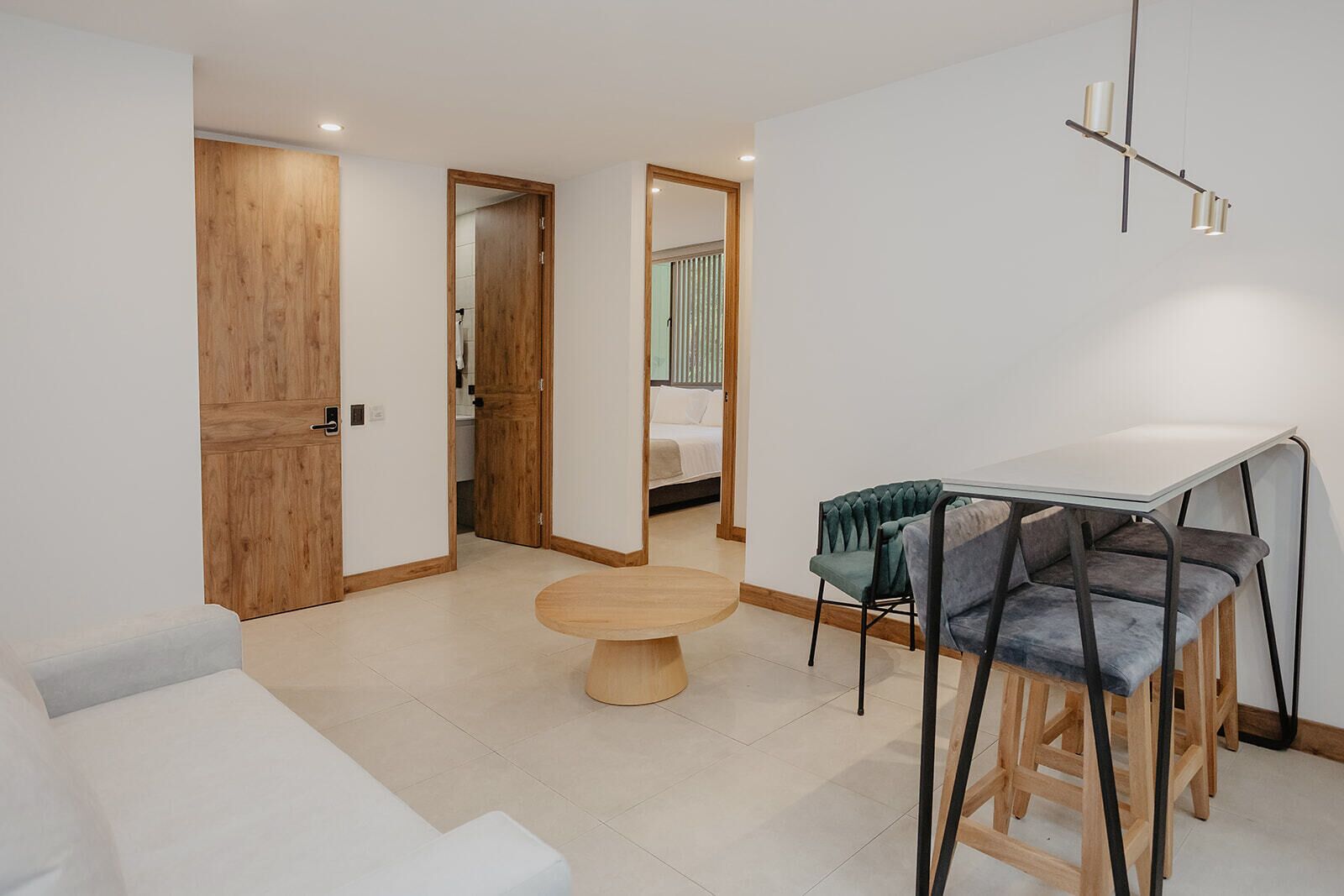 A modern room with a wooden door, a round table, and a small dining area with stools.