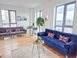 Una sala de estar moderna con un sofá gris, un sofá azul y una mesa de centro redonda.