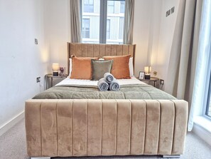 A neatly made bed with a headboard, two bedside tables with lamps, and a window with curtains. - Lux 3-Bedroom Battersea Penthouse w/ 3 Private Balconies near Clapham, Nine Elms (London)