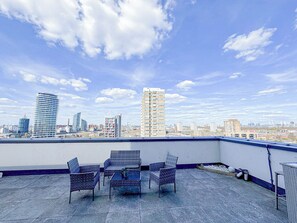 A rooftop terrace with a view of a city skyline, featuring modern buildings and a clear sky. - Lux 3-Bedroom Battersea Penthouse w/ 3 Private Balconies near Clapham, Nine Elms (London)