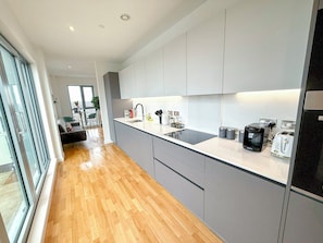 A modern kitchen with grey cabinets, a black induction cooktop, and a toaster.