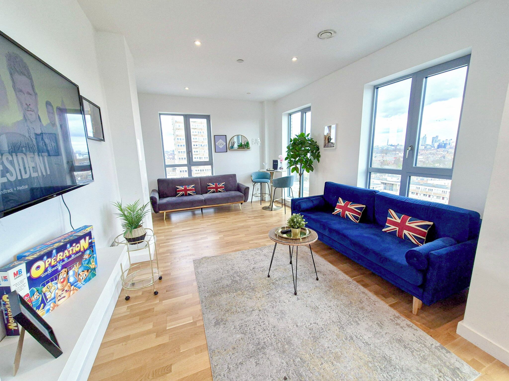 A modern living room with a blue sofa, a wooden coffee table, and a television mounted on the wall.