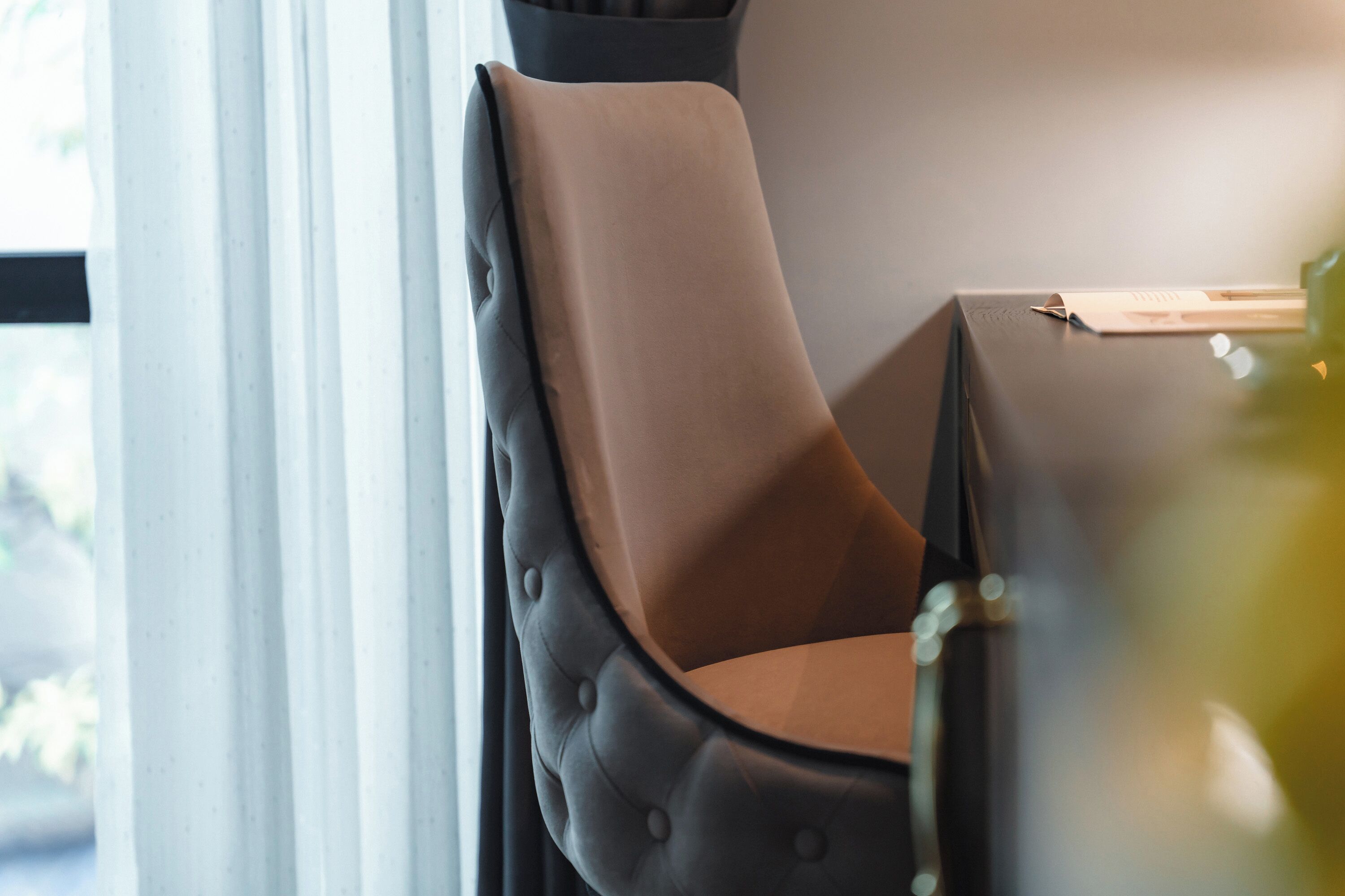 A chair with a cushioned backrest and a dark frame, positioned next to a table with a document on it.