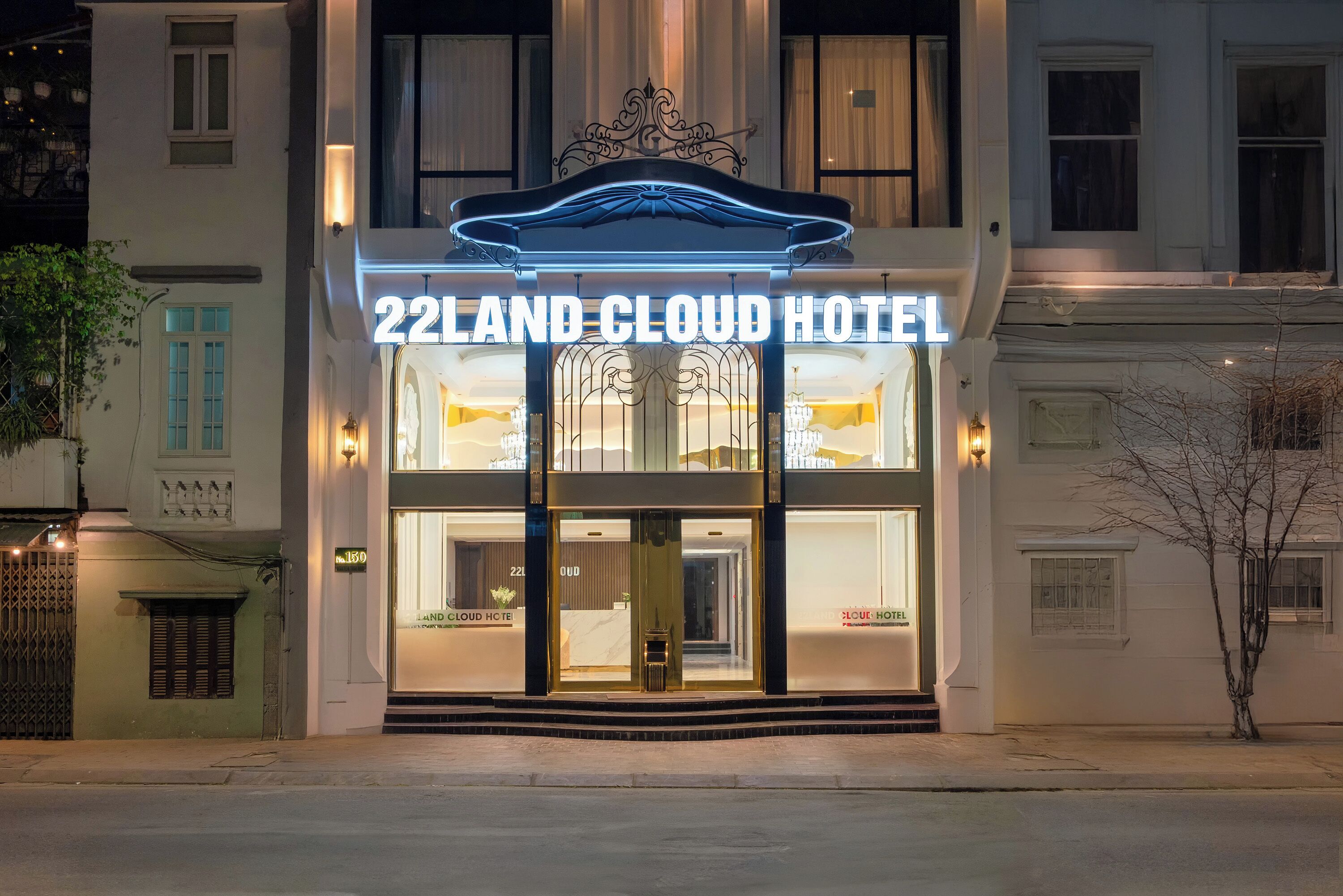 Das äußere Erscheinungsbild des 22Land Cloud Hotels mit einer auffälligen beleuchteten Signatur, großen Fenstern und einem klassischen architektonischen Design.