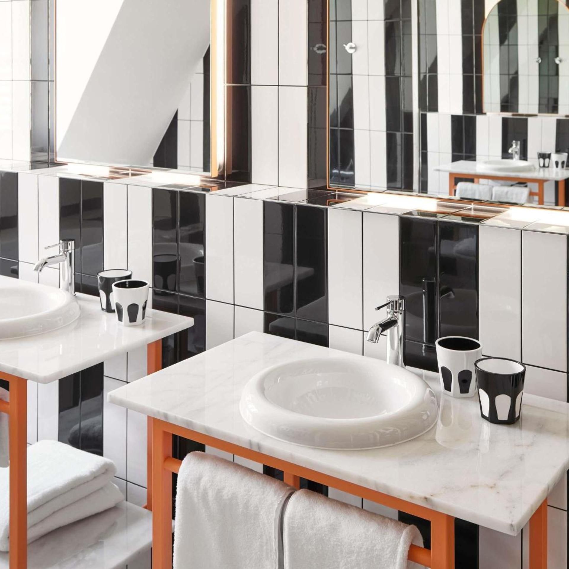Une salle de bain moderne avec deux lavabos, un grand miroir et un porte-serviettes.