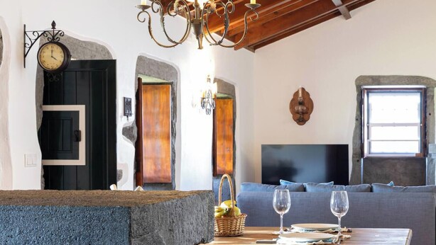 Un intérieur rustique avec un banc en pierre, une table en bois et un lustre.