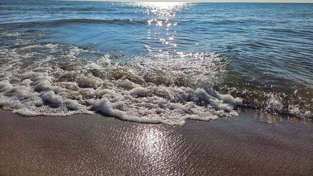 Een strand met golven die zachtjes op de kust spoelen.
