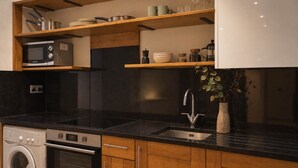 A modern kitchen with a built-in oven, microwave, and dishwasher, wooden cabinets, and a black countertop. - Newly refurbished, Superior studio Lower Ground (London)