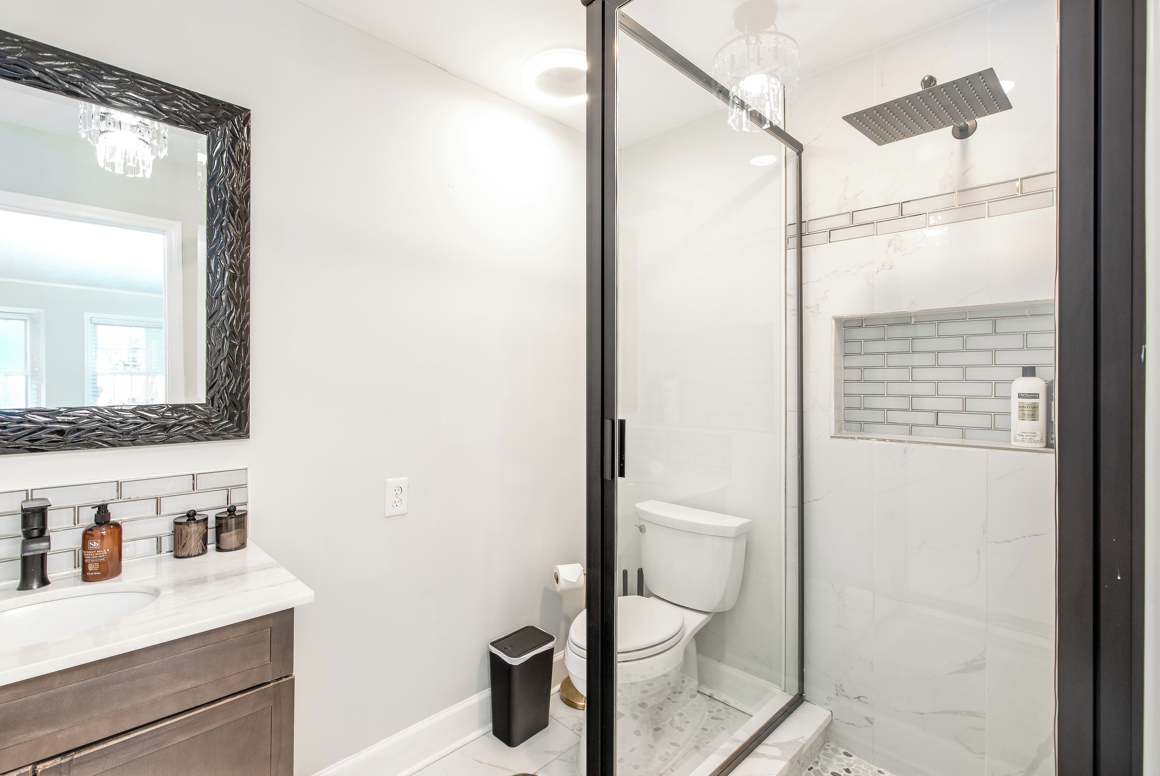 Een moderne badkamer met een douchekabinet van glas, een wit toilet en een douchegedeelte betegeld met marmer.