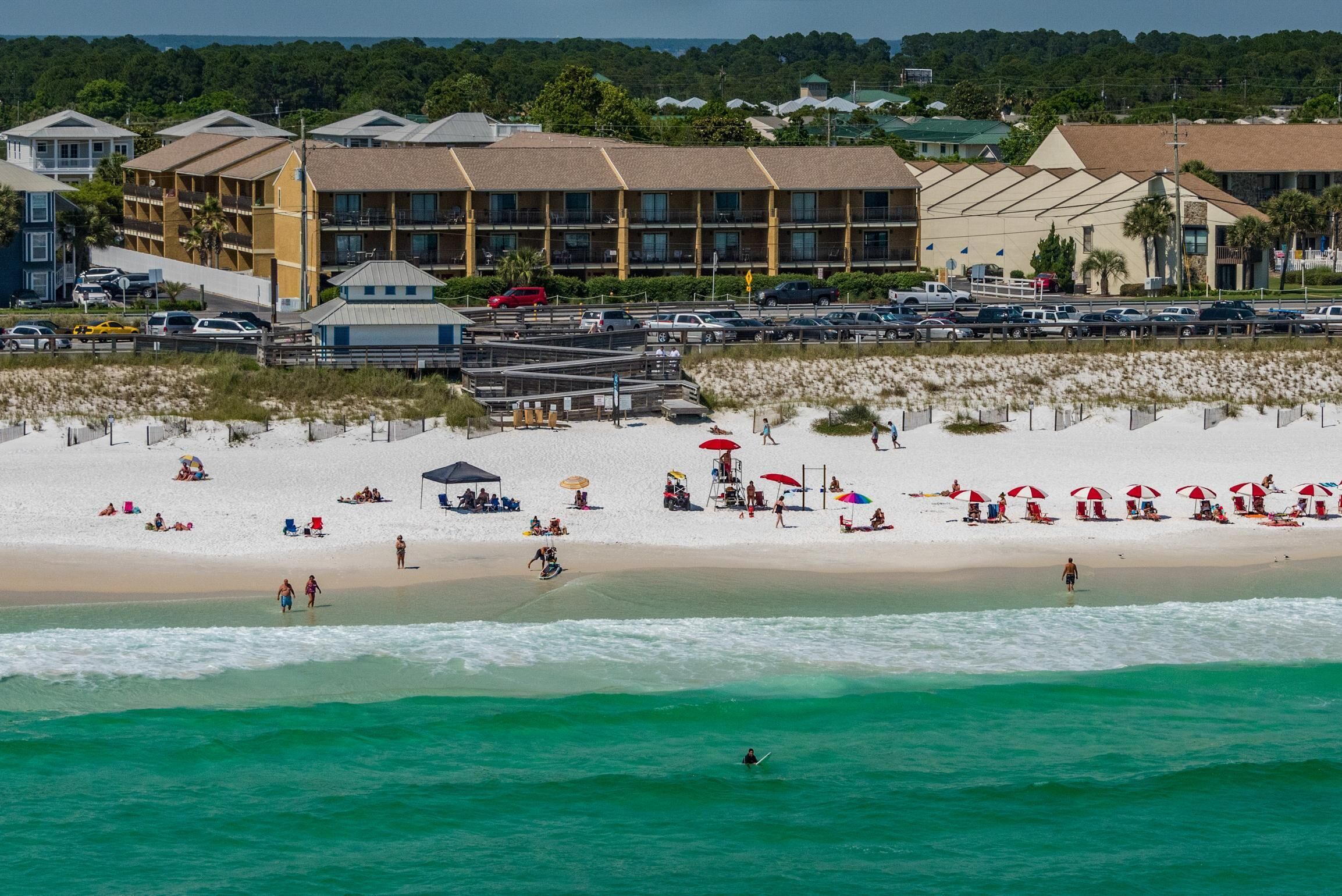 Ein Strandhotel mit mehreren Gebäuden, einem Sandstrand und einem Parkplatz.