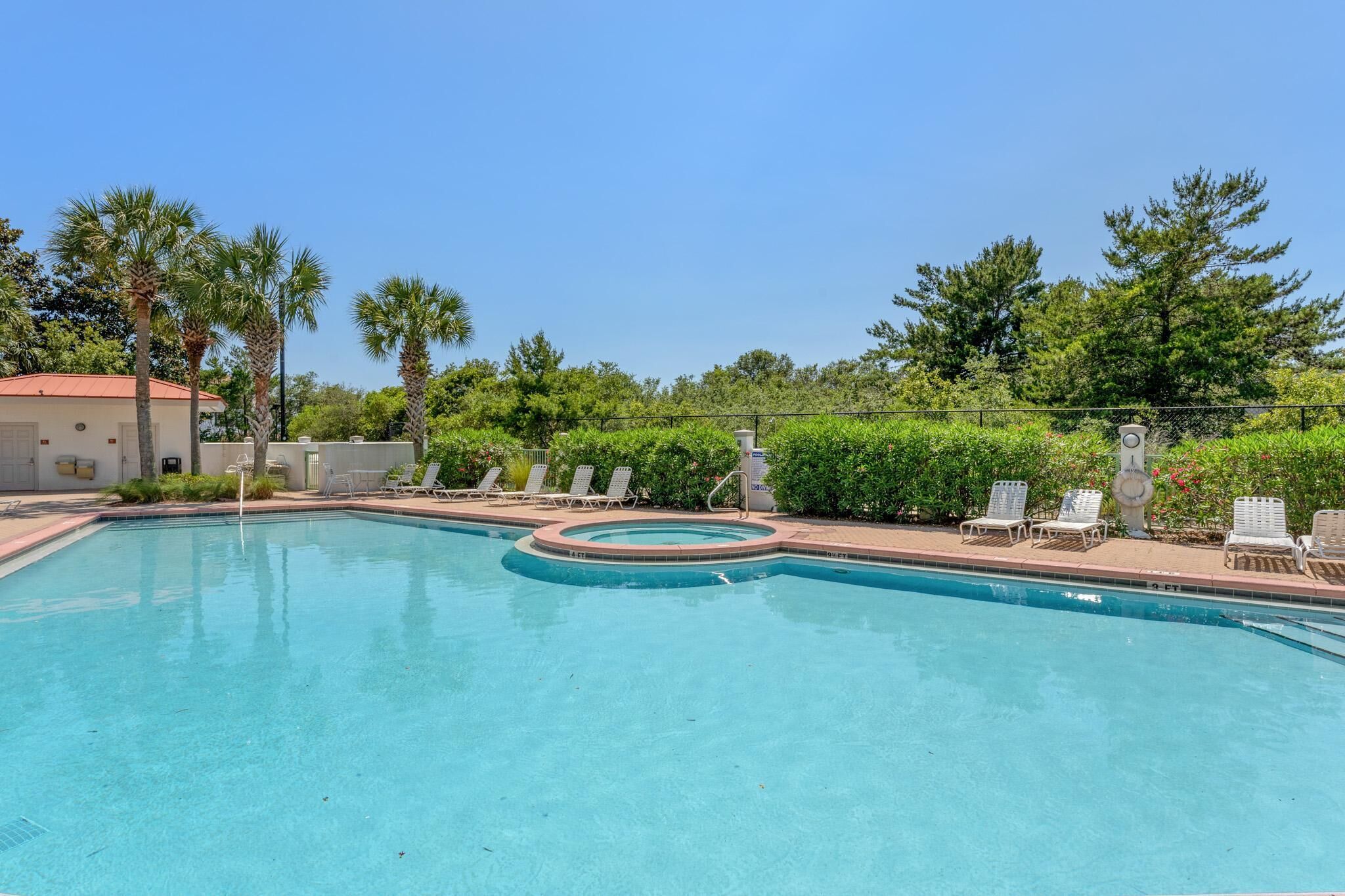A swimming pool with lounge chairs and a building in the background.