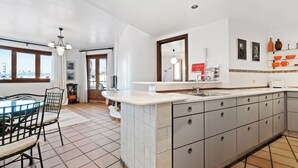 A modern kitchen with a large island, white cabinetry, and a view through the windows. - Punta Prima Beach Apartment Kenya (Punta Prima)