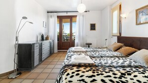 A hotel room with a bed, a desk, a lamp, and a view of the outside. - Punta Prima Beach Apartment Kenya (Punta Prima)