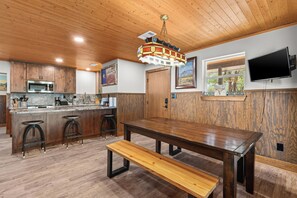 A modern kitchen with wooden cabinets, a stainless steel oven, and a bar area with stools. - Ping Pong and Foosball; kitchen and bathrooms shared amenities (Dripping Springs)