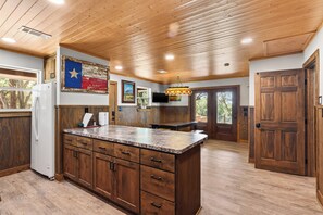 A kitchen with wooden cabinets, a granite countertop, and a Texas state flag decoration.