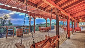 Eine Holzterrasse mit einer Schaukel, Stühlen und Tischen mit Blick auf eine schöne Landschaft.