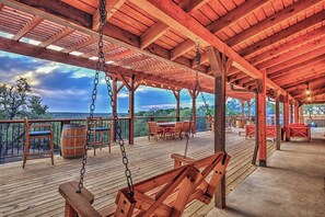 Une terrasse en bois avec une balançoire, des chaises et des tables, offrant une vue sur un paysage magnifique.