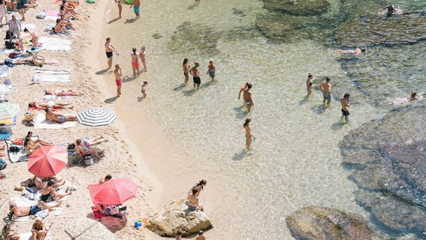 A beach with people sunbathing, swimming, and walking along the shore. - Lloret de Mar Camping (Lloret de Mar)