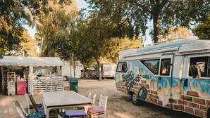 A campsite with a dining area, a white table, and chairs, and a camper with graffiti. - Lloret de Mar Camping (Lloret de Mar)
