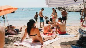 A beach scene with people relaxing on towels and under umbrellas. - Lloret de Mar Camping (Lloret de Mar)