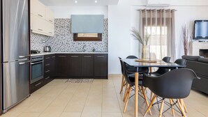 Eine moderne Küche mit dunklen Schränken, einem Edelstahlkühlschrank und einer gefliesten Spritzschutzwand.