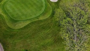 An aerial view of a golf course with well-maintained greens, sand bunkers, and a winding path.